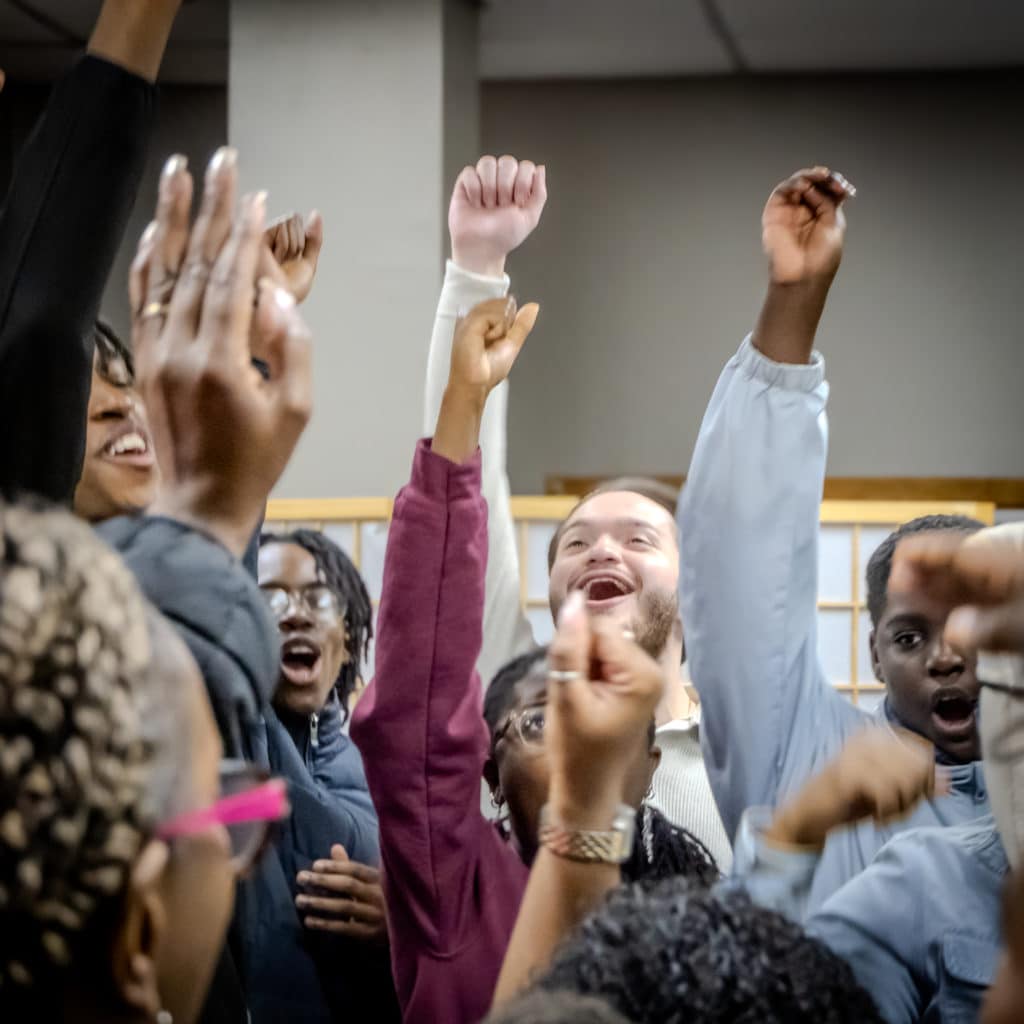 G-Squad volunteers with hands raisedduring a morning huddle